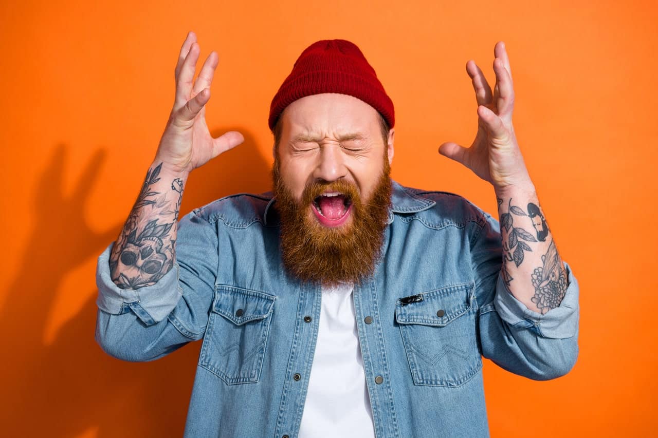 Bearded man expressing frustration with raised hands