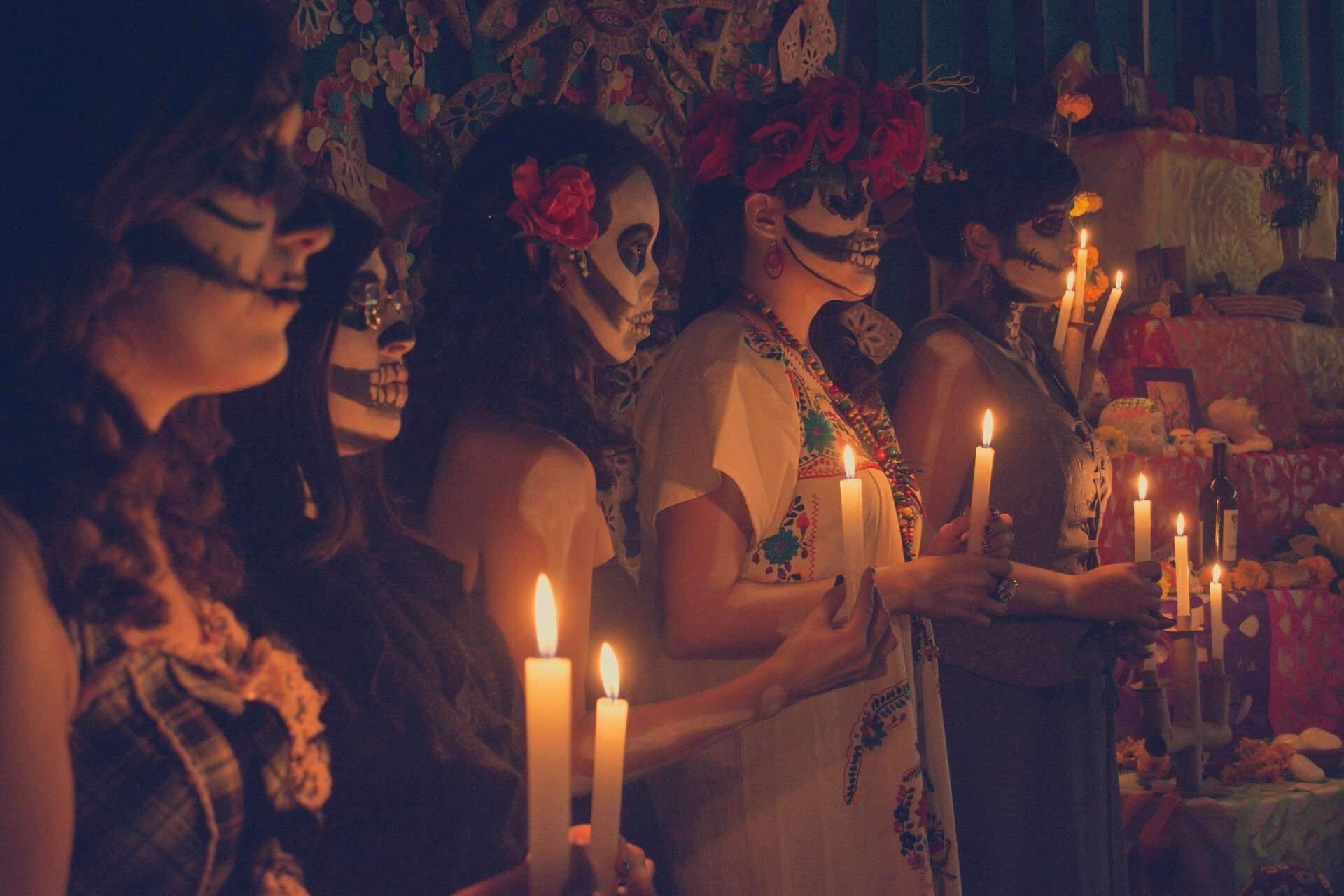 People wearing skull paintings on their faces and bringing offerings to the altar in the Day of the Dead in Mexico