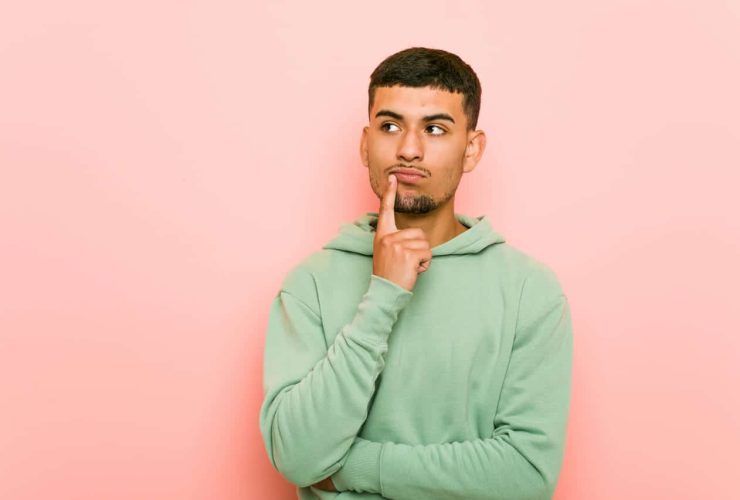 Man in a green hoodie thinking with finger on chin