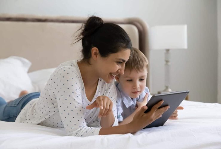 A mother and child using a tablet together on a bed