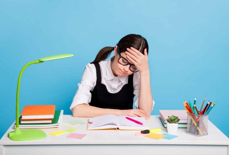 Girl in glasses looking frustrated while studying at her desk