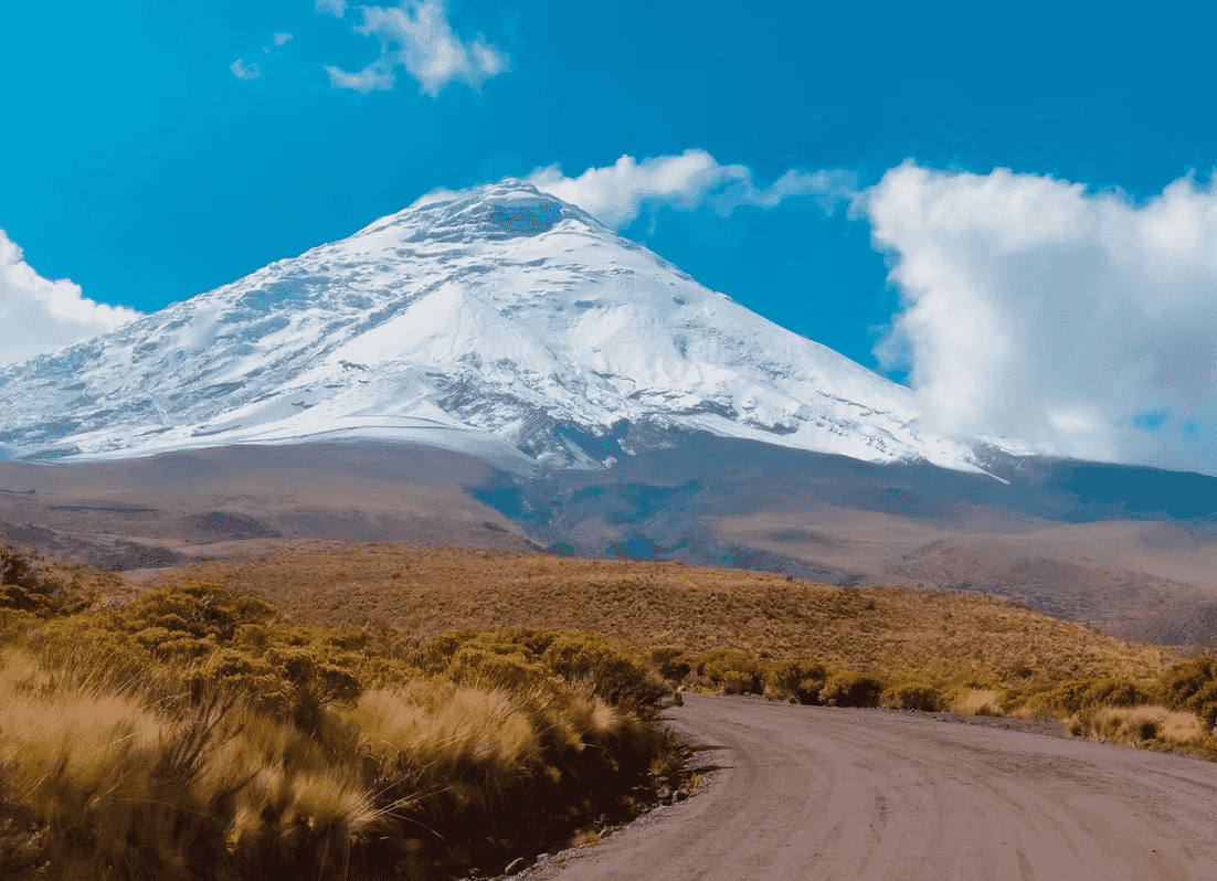 Snow-capped mountain with a dirt road and blue sky