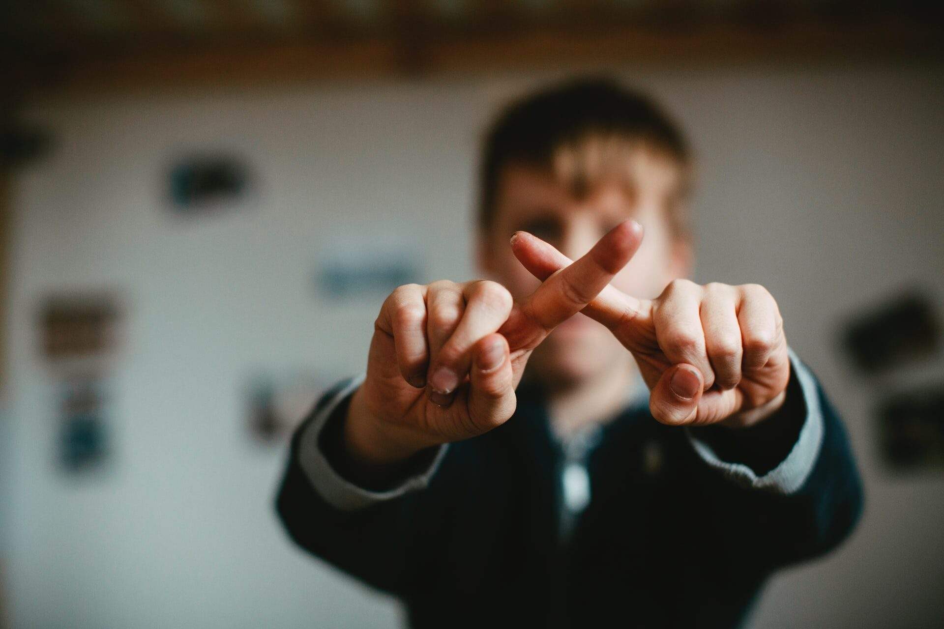 Boy making an “X” shape with his fingers