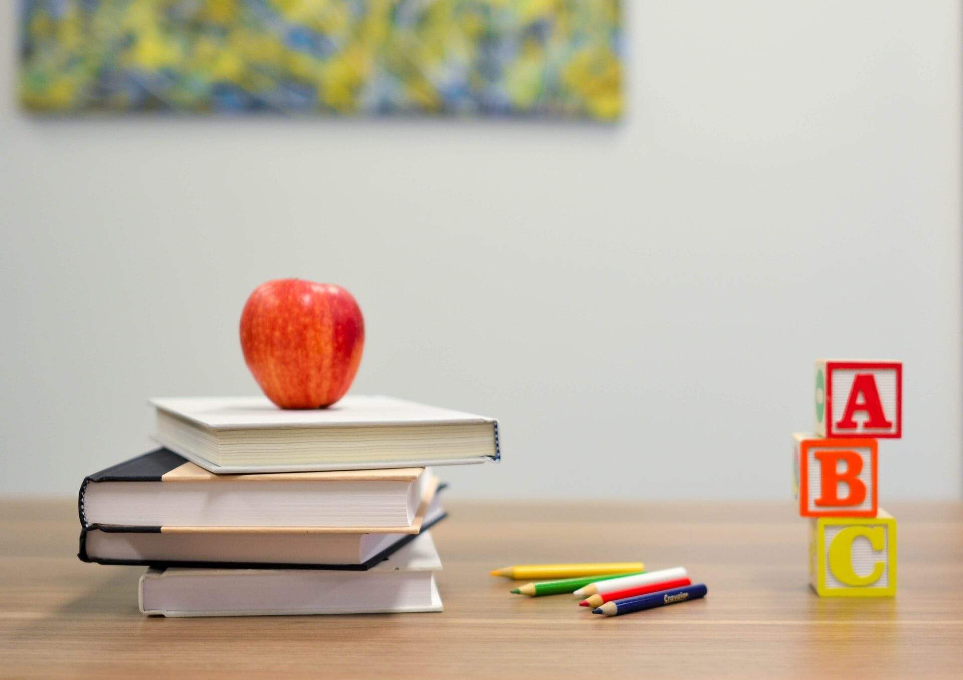 Stack of books with an apple on top and alphabet blocks