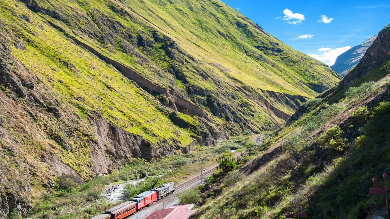 Train traveling through a lush green valley surrounded by hills