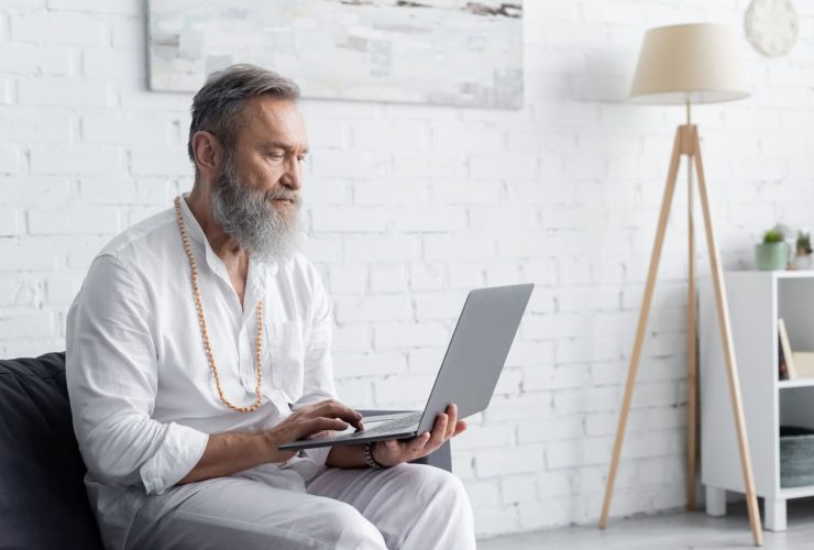 Elderly man with beard using a laptop at home