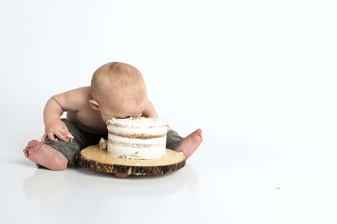 Baby face-first into a cake on a wooden stand