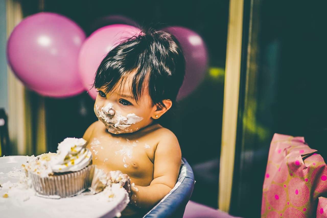 Baby with cake frosting on face and hands