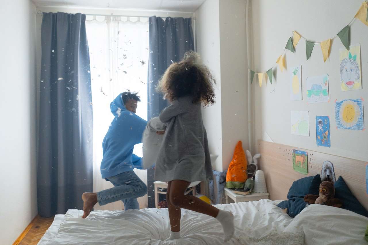 Two kids having a pillow fight on bed