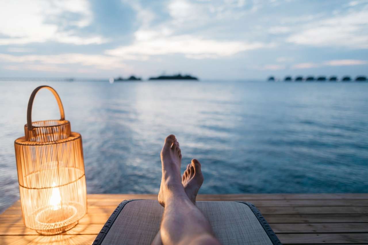 Person relaxing by the water with lantern