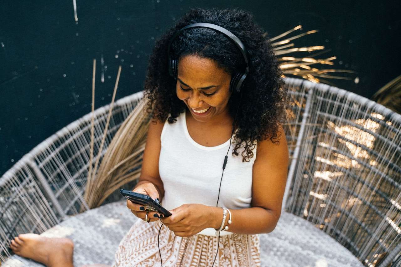 A woman smiling while listening to music on headphones