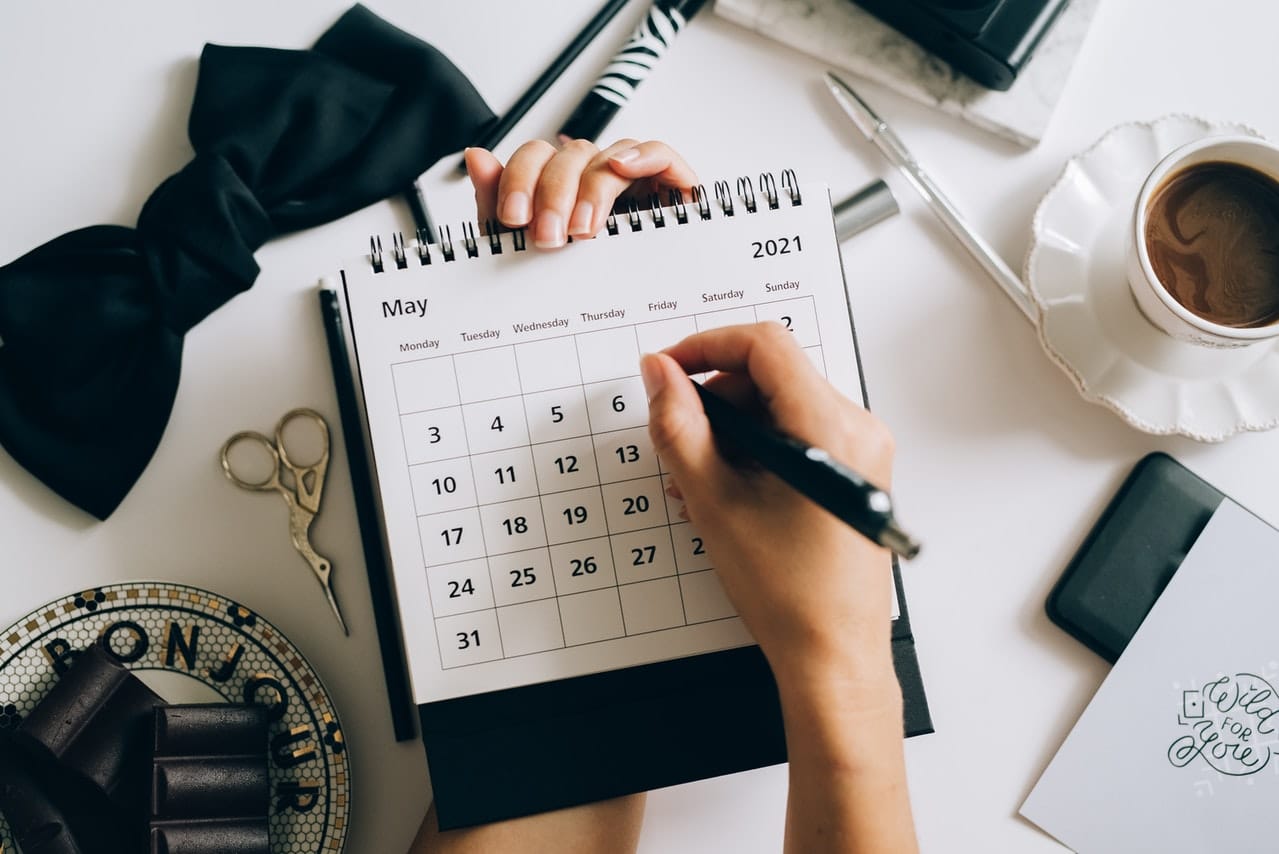 Hand marking dates on a calendar with a pen