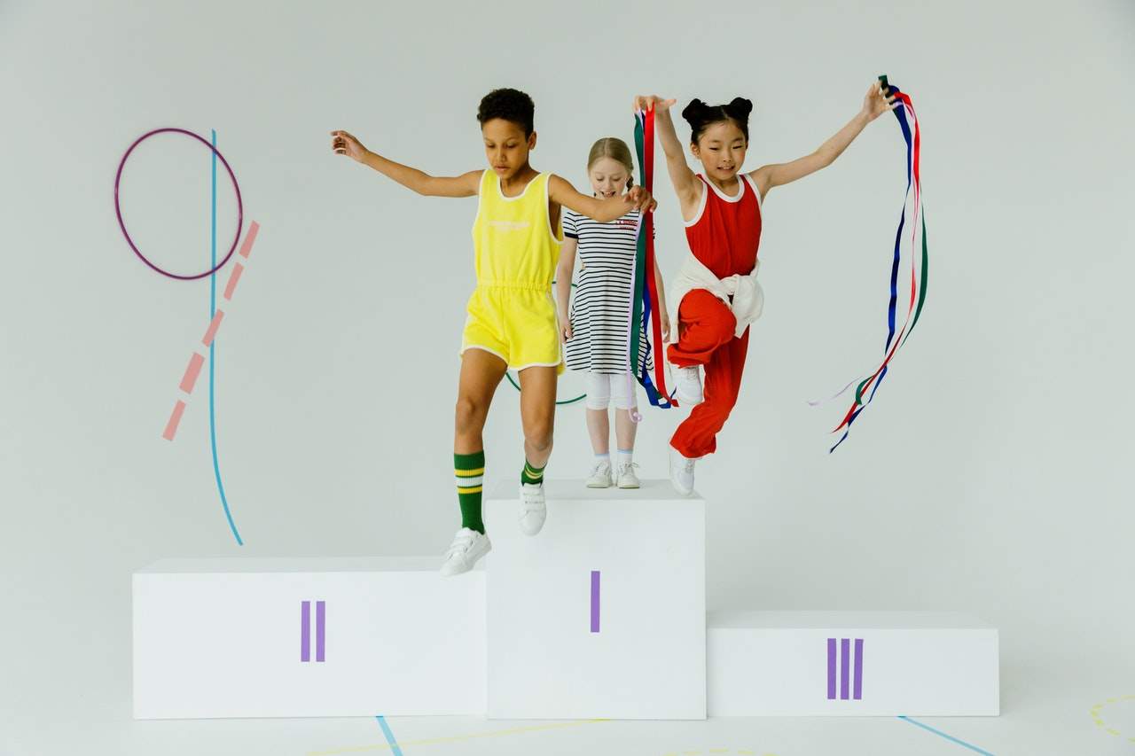 Three children playing and balancing on white platforms