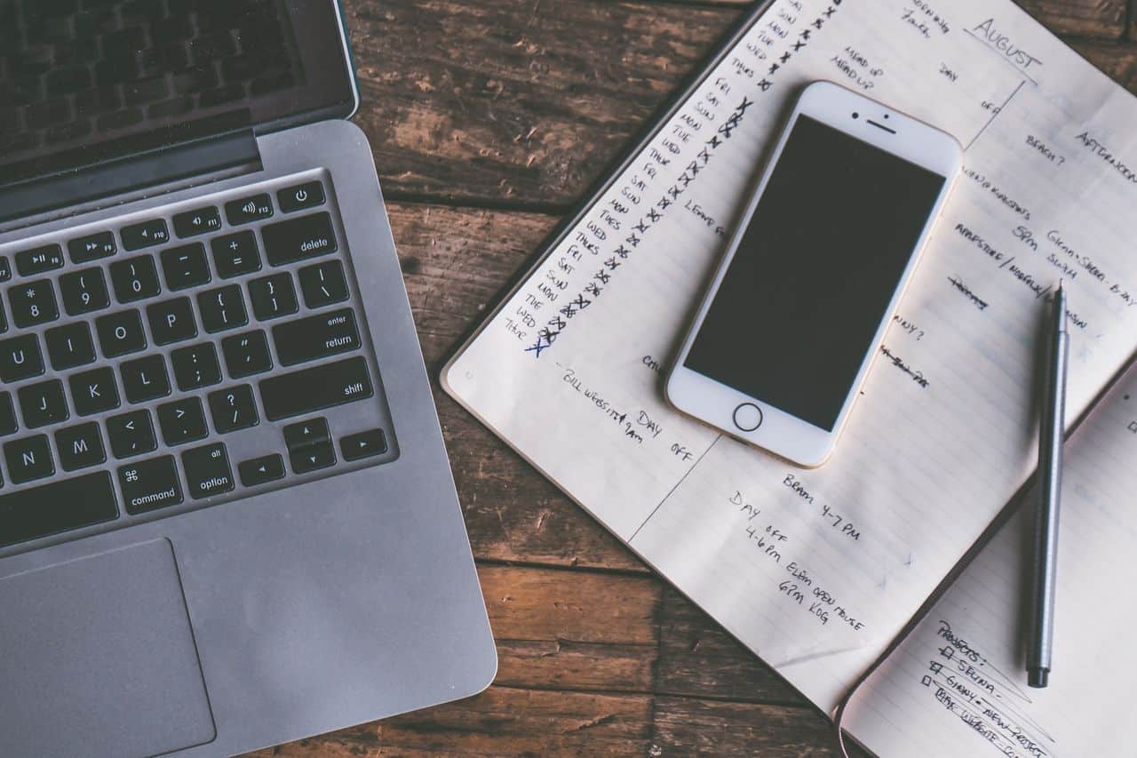 Laptop, phone, and notebook on a wooden desk