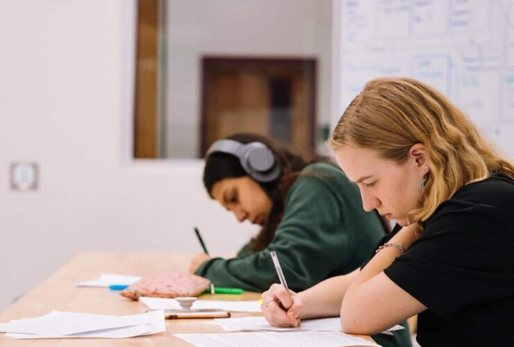 Two students are sitting at a desk, focused on their work