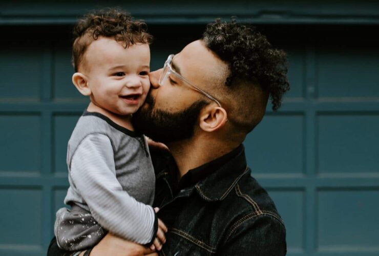 Person holding and kissing a happy baby