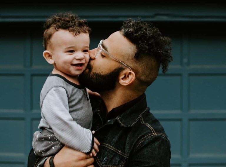 Person holding and kissing a happy baby