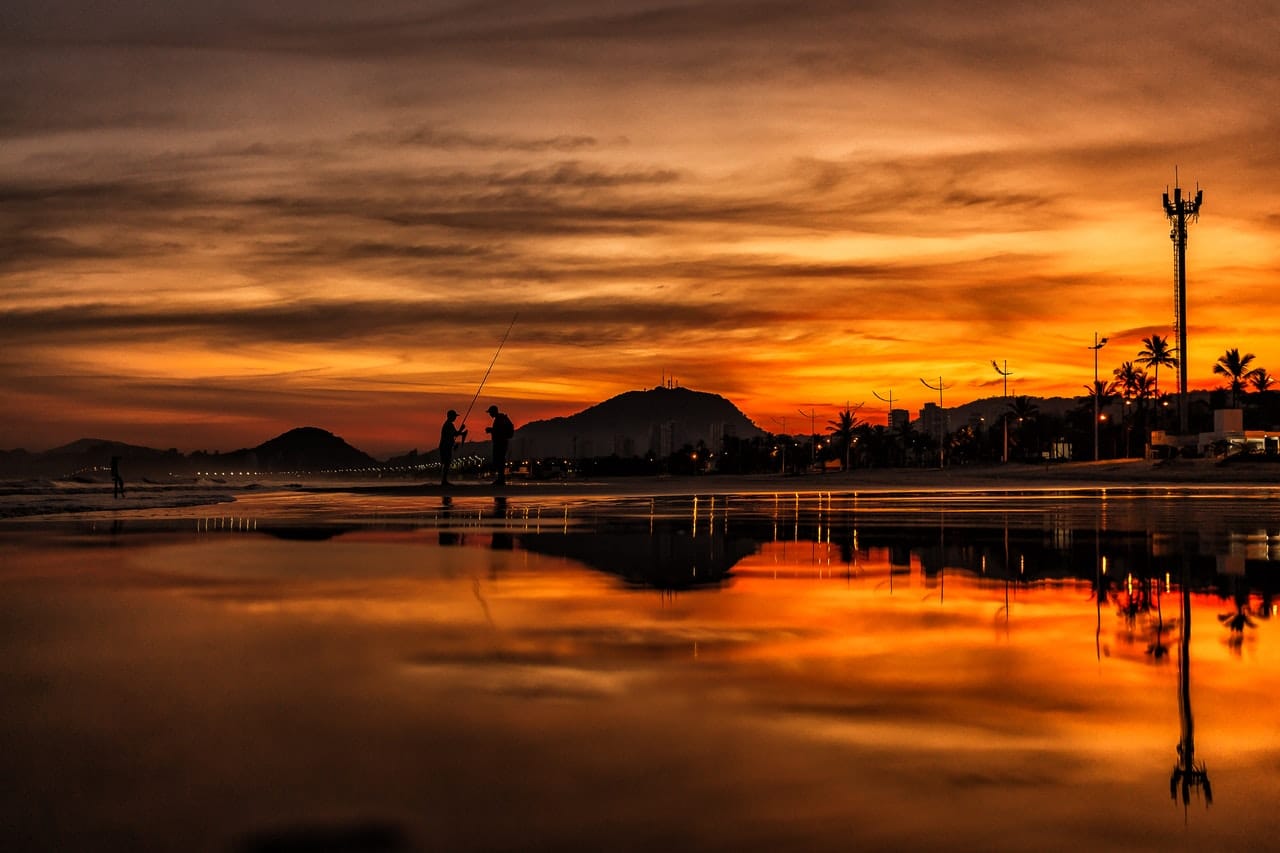 Sunset reflecting on a beach with two fishermen