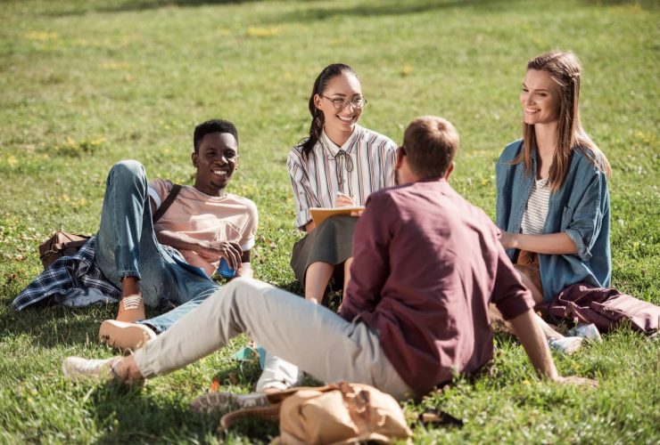 Group of friends sitting and talking together on the grass