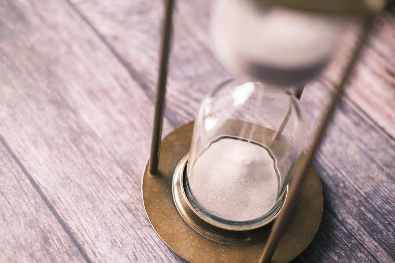 Hourglass with sand running on a wooden surface