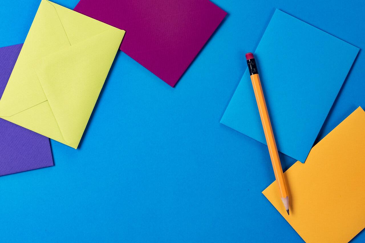 Colorful envelopes and pencil on blue background