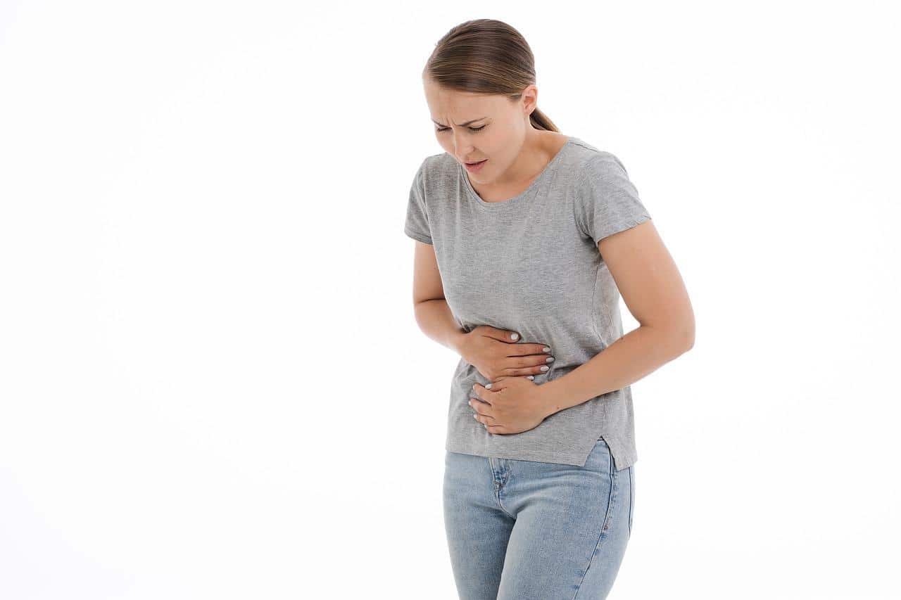 A woman holding her stomach and appearing to be in pain