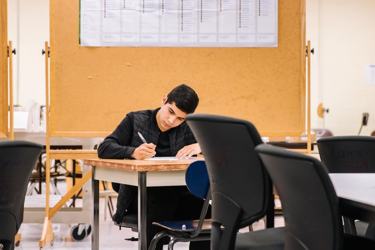 Student writing in a classroom with focus