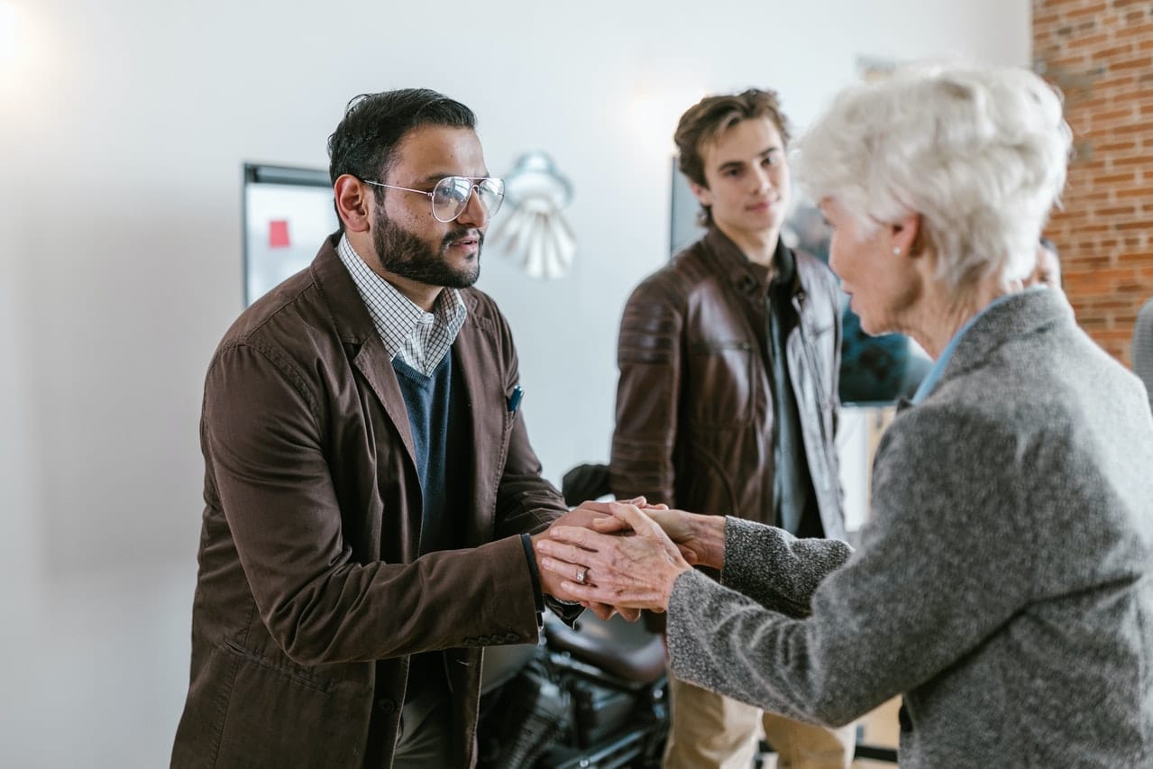 A man shaking hands with an elderly woman