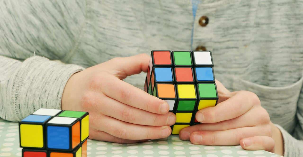 Hands holding and solving a colorful Rubik's cube