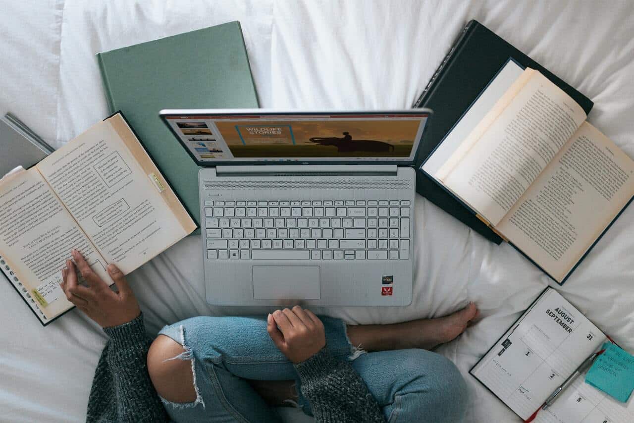 Person sitting with laptop and open books