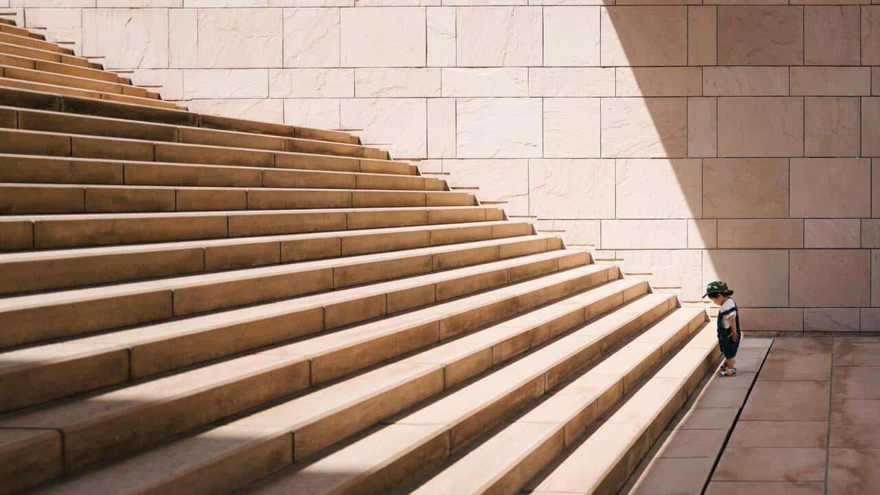 A child standing at the bottom of large stairs