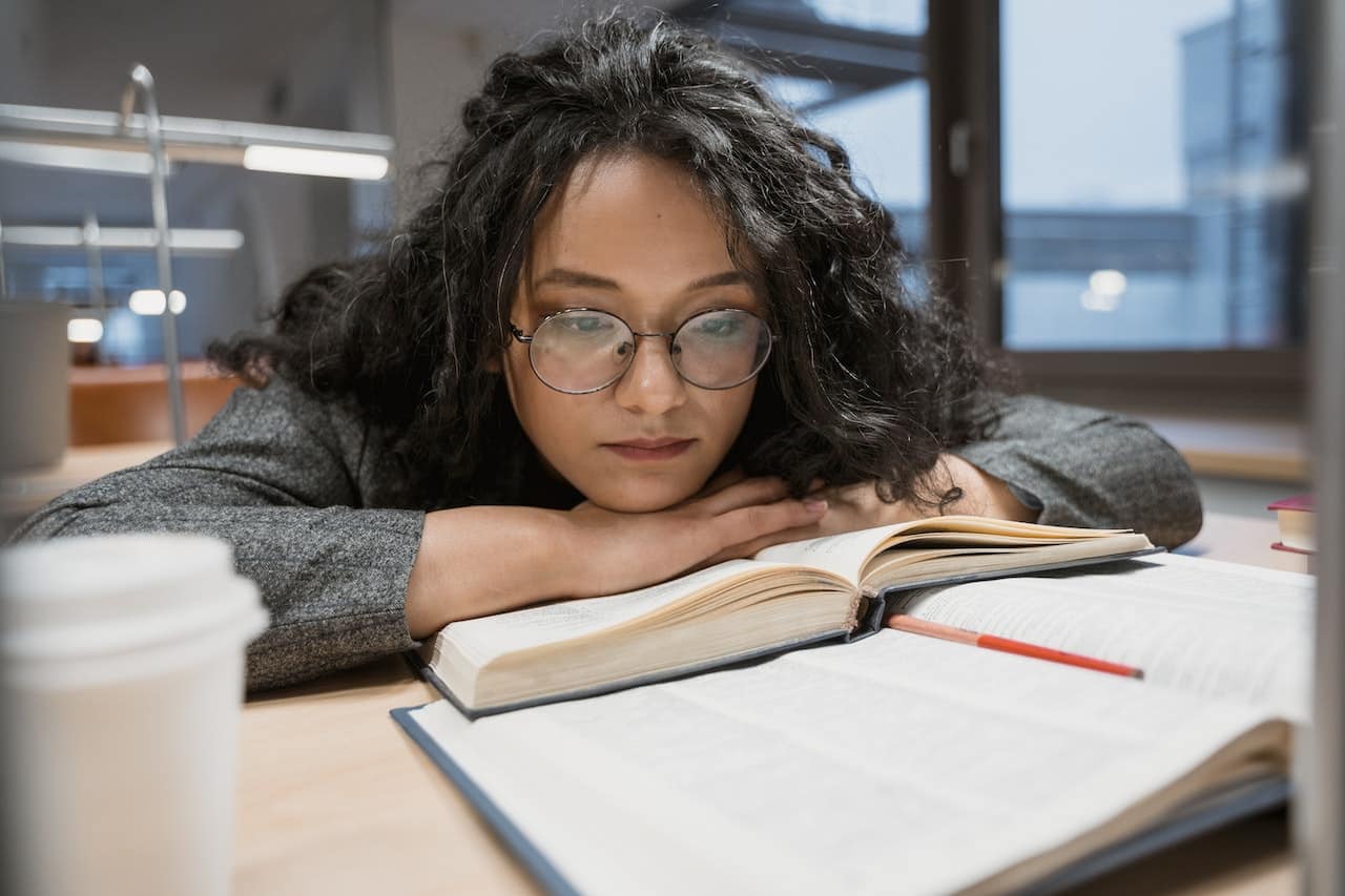 Person reading a book while resting their head on hands