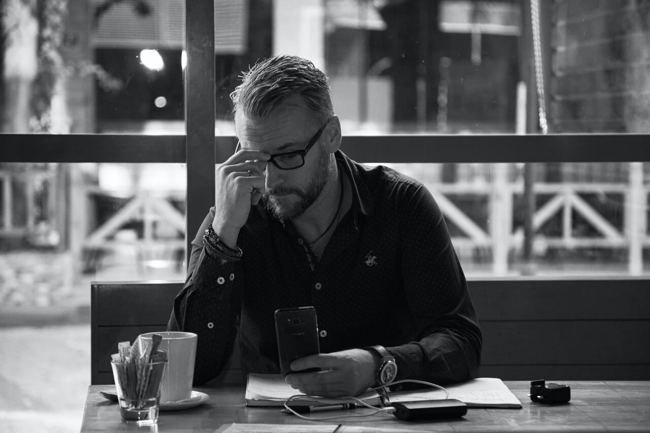 Man sitting at a table holding a phone in hand