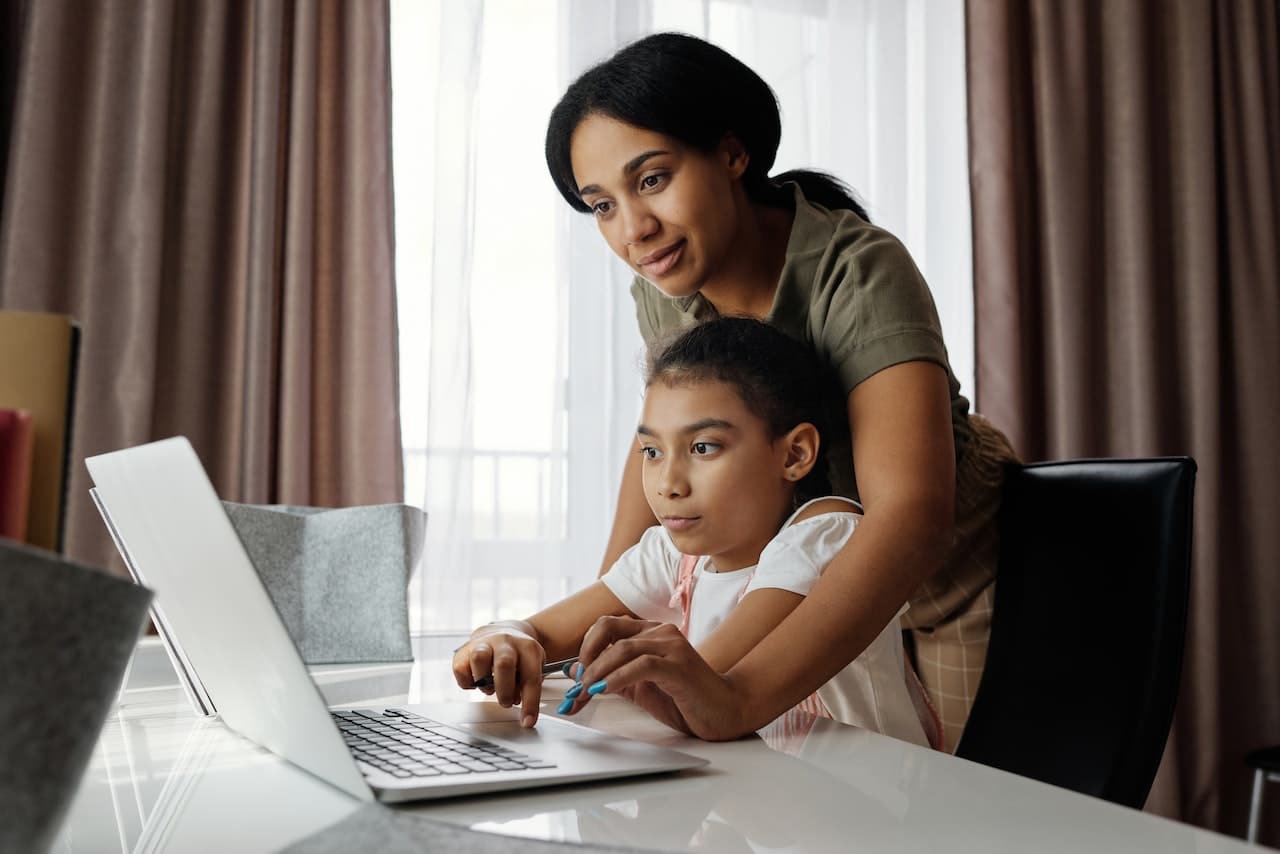 Mother helping child use a laptop computer