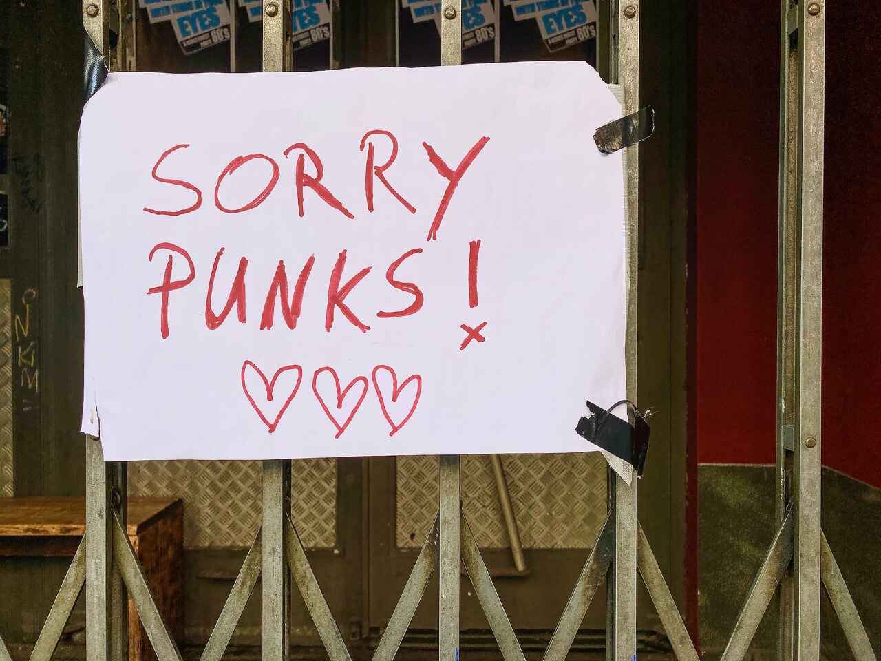 Handwritten sign on a gate reading sorry punks hearts