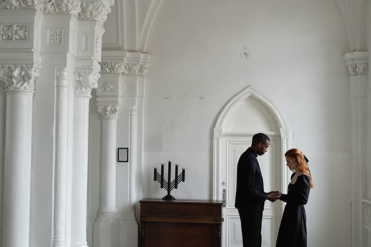 Two people standing together in a white ornate room