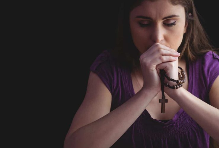 Woman praying while holding a rosary