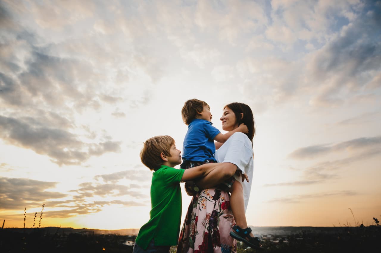 Woman holding a child with another child nearby