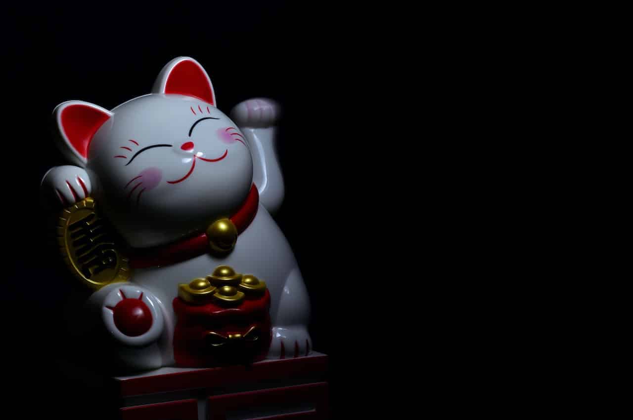 Waving Maneki-neko cat in dark background