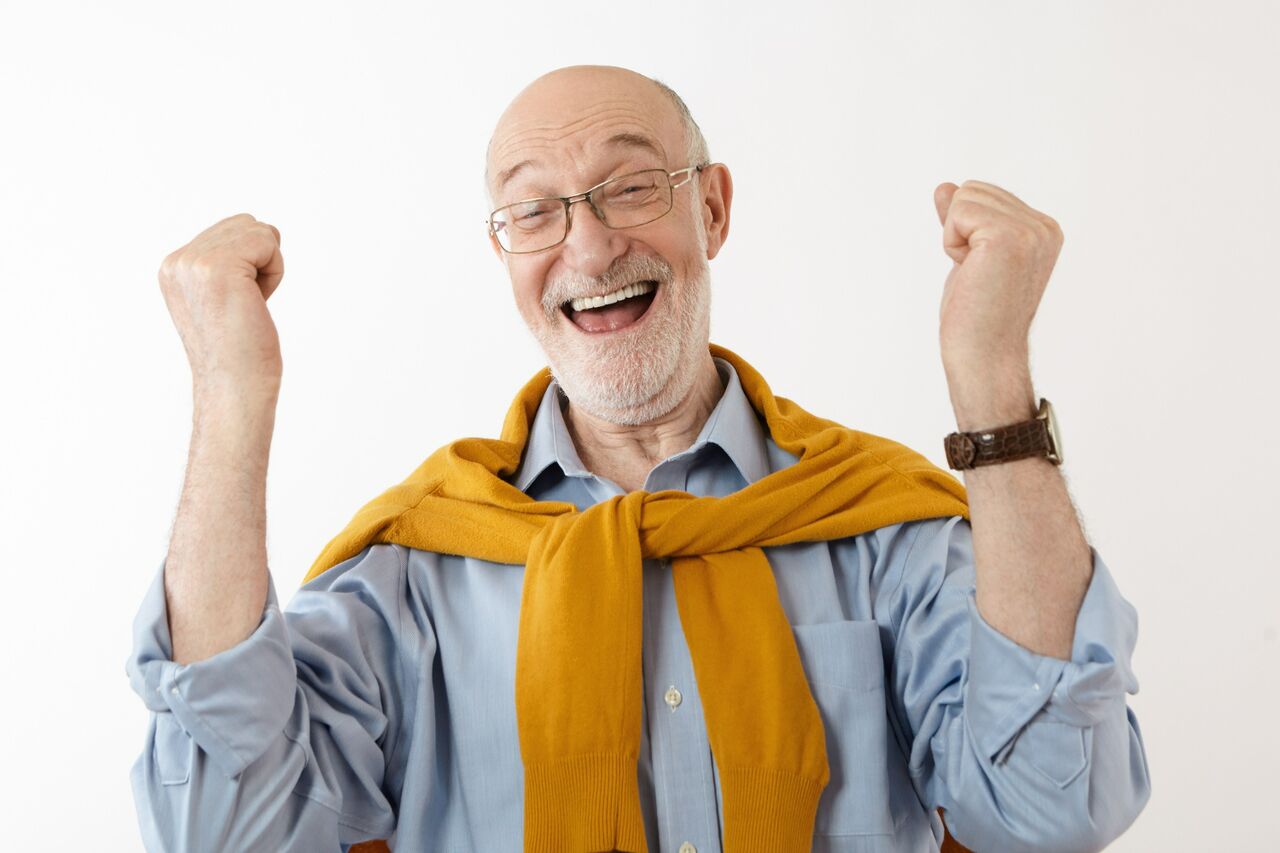 Elderly man smiling with fists raised in excitement