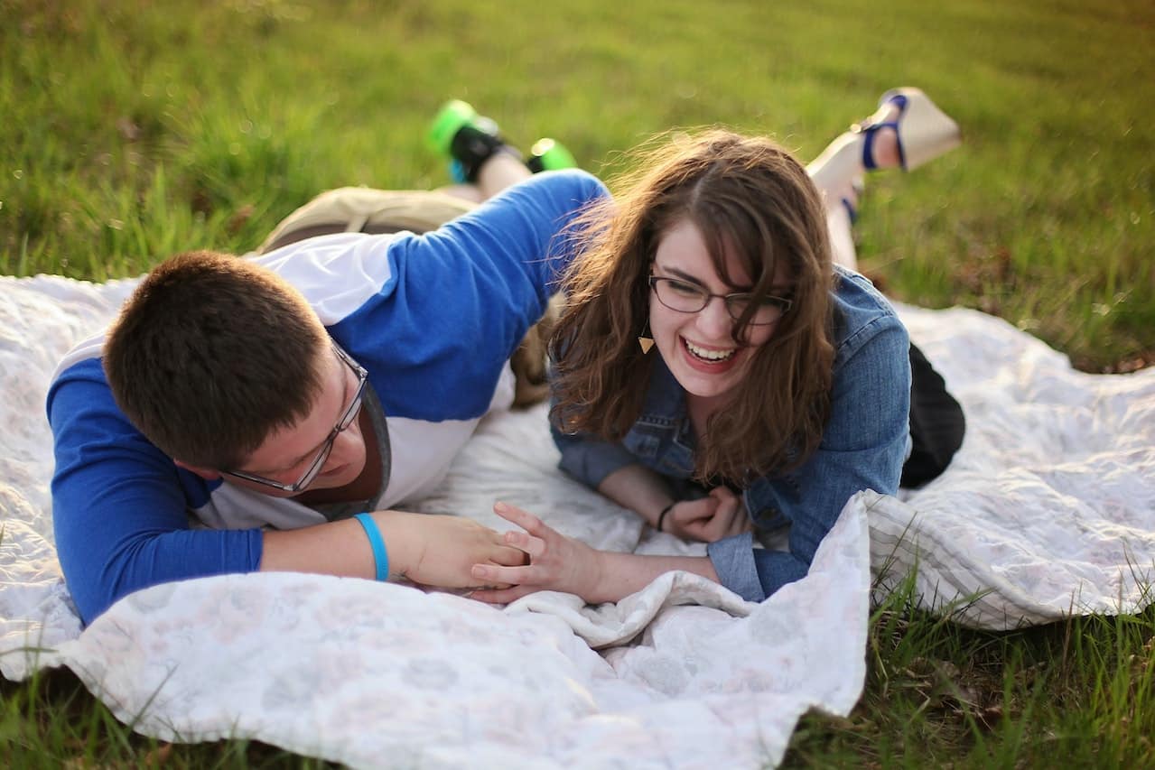 Couple laughing together on a blanket in a field