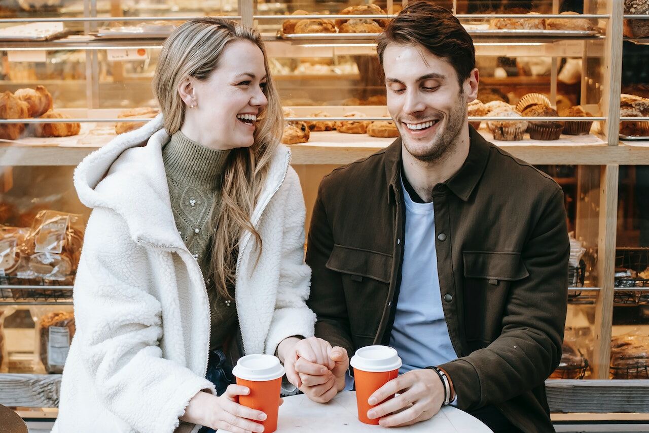 Couple holding hands and enjoying coffee outdoors