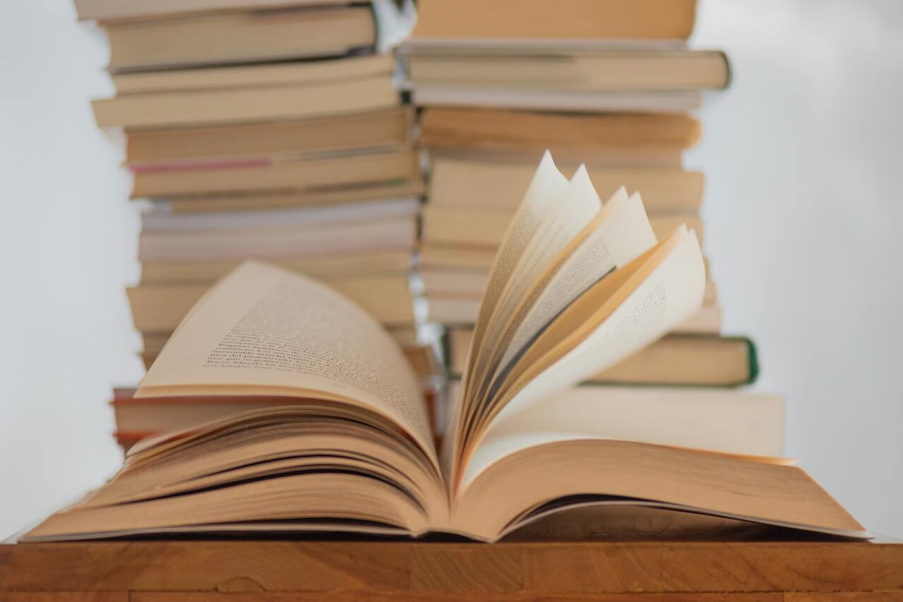 Open book on a table with stacked books