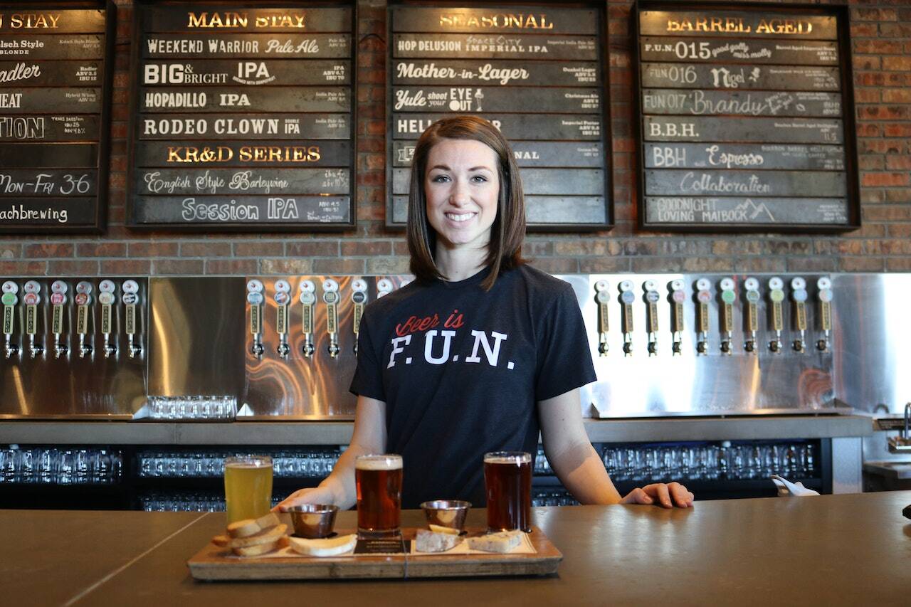 Bar staff member smiling behind the bar with drinks