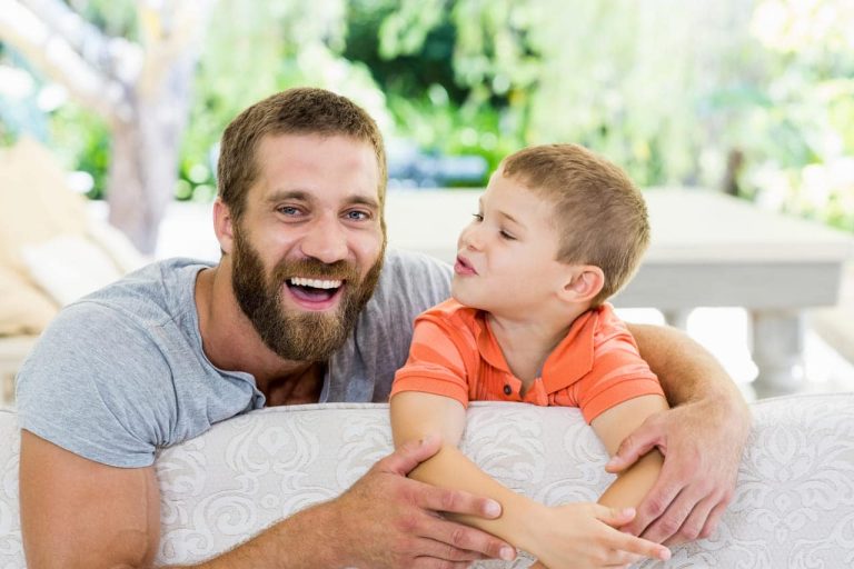A father and son smiling together on a couch