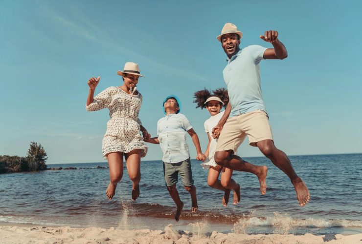 A family happily jumping on a beach.