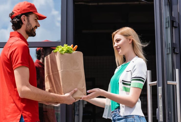 A delivery person handing groceries to a woman