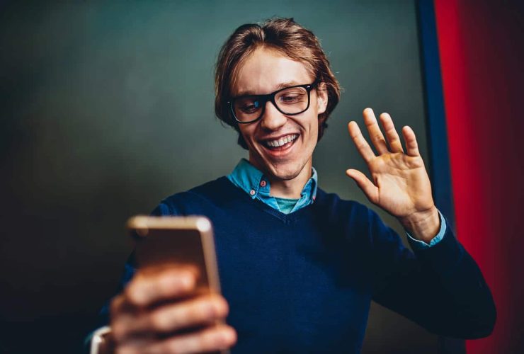 Man smiling and waving while on a video call using a smartphone