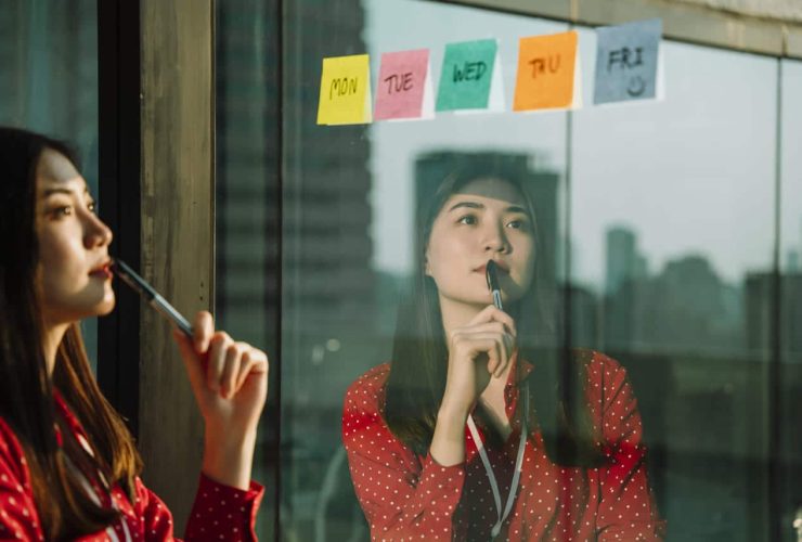 Woman reflecting while looking at sticky notes with days of the week