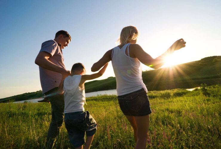 Family walking together in a field during sunset